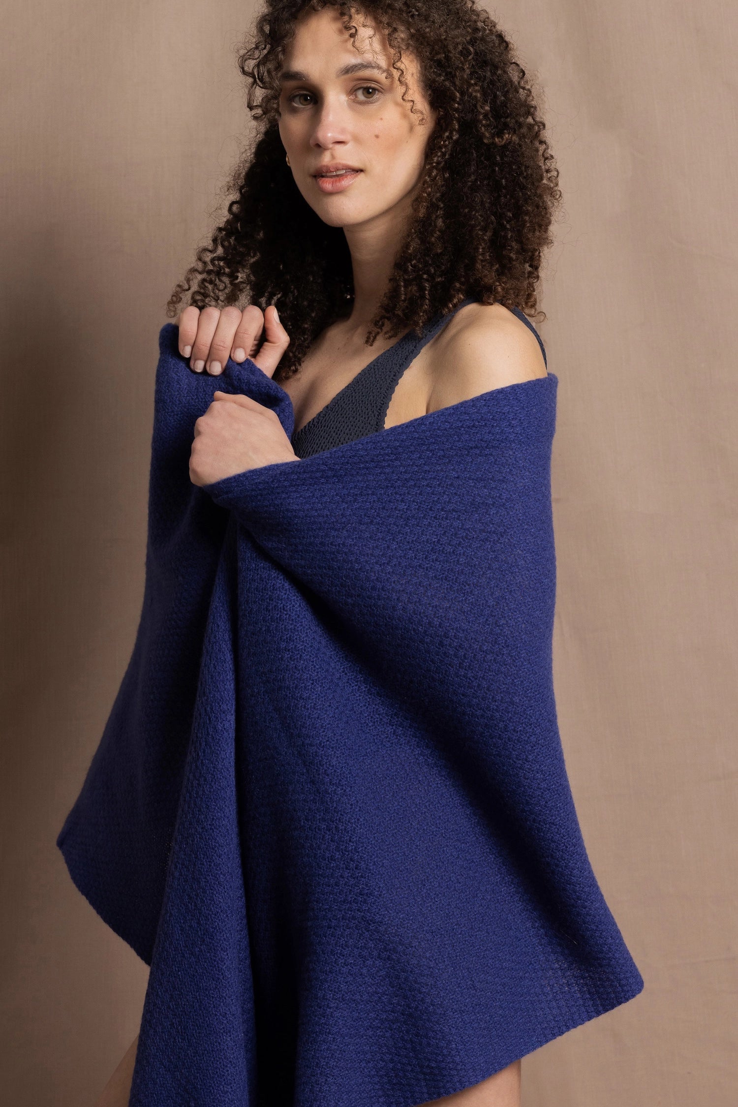 A woman wears a bright blue cashmere shawl wrapped around her