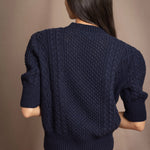 a woman wearing a cashmere aran sweater tee in navy blue with orange silk skirt