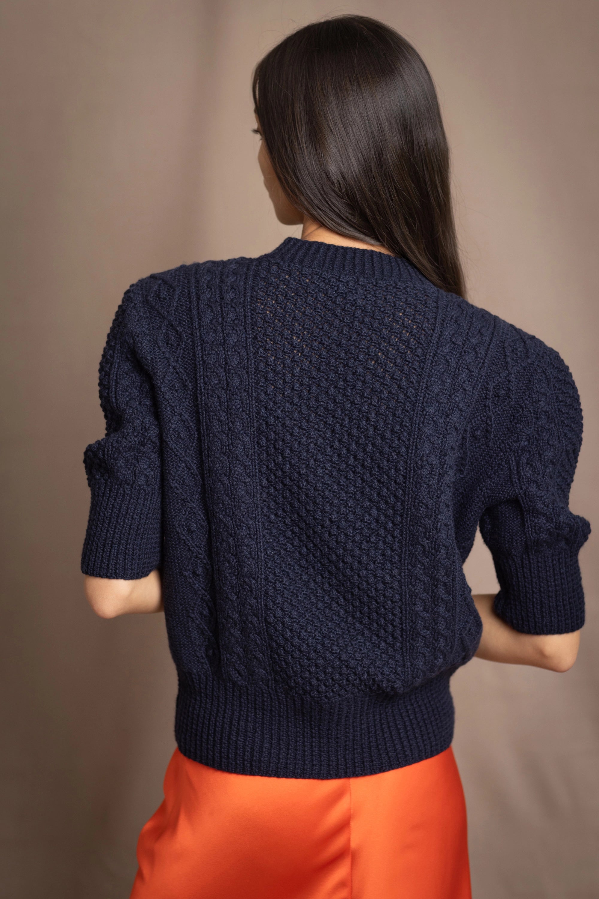 a woman wearing a cashmere aran sweater tee in navy blue with orange silk skirt