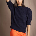 a woman wearing a cashmere aran sweater tee in navy blue with orange silk skirt