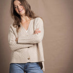 A lady wears a traditional Irish Cashmere Aran Cardigan Sweater in Beige