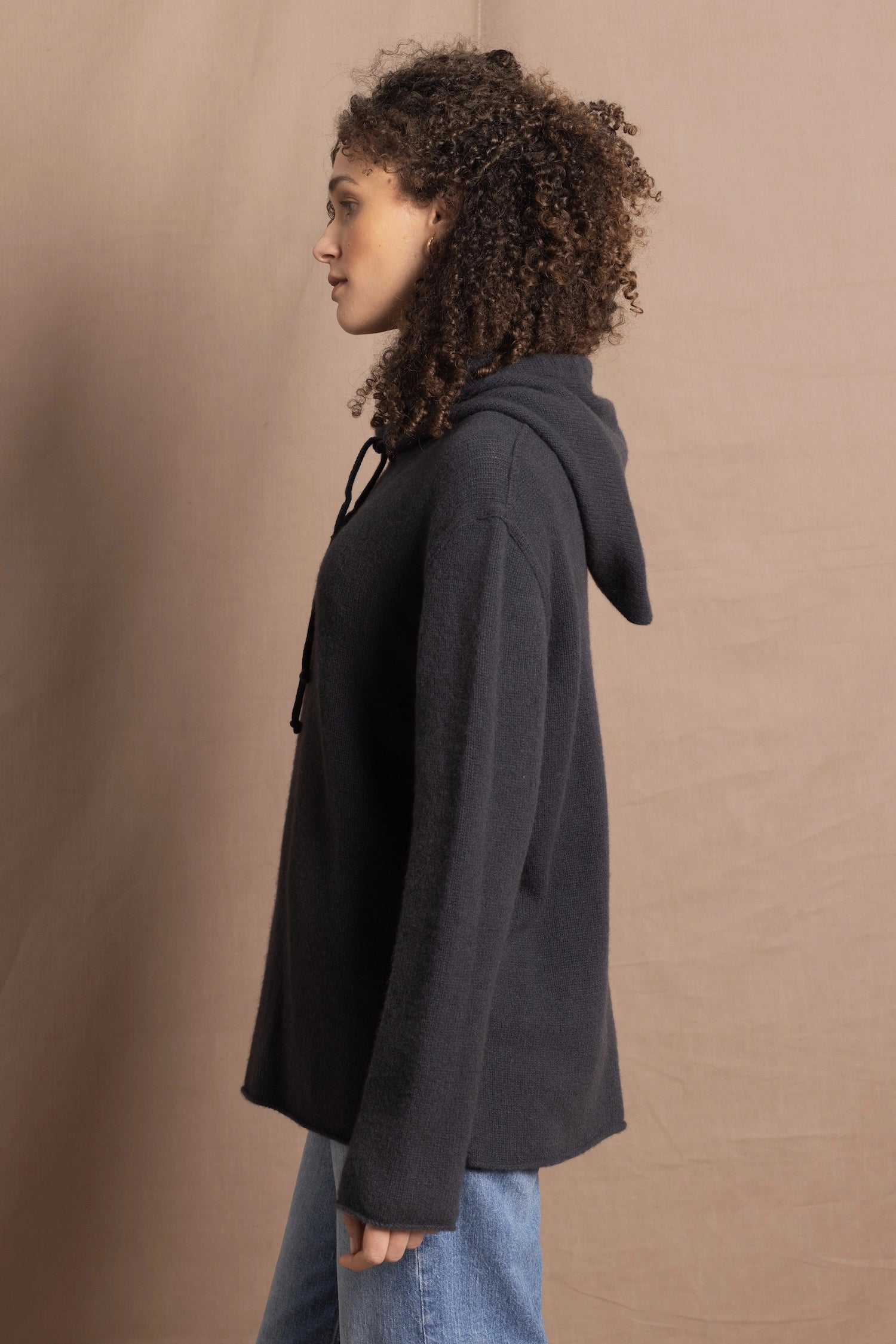lady looks sideways wearing an oversized pure cashmere hoodie sweater in grey blue colour