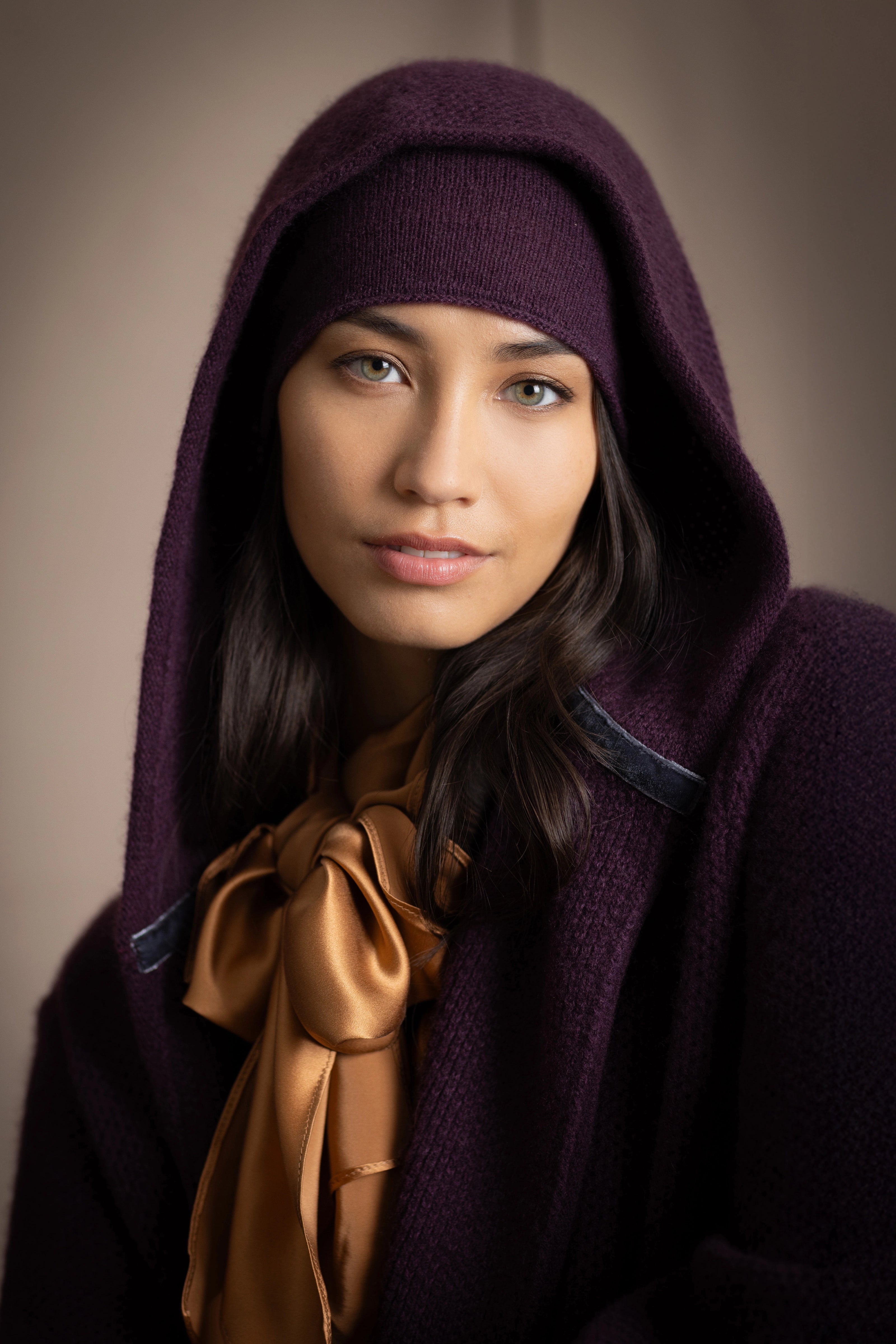 Woman wearing a cashmere hooded cardigan coat and cashmere beanie hat in dark purple with gold silk top