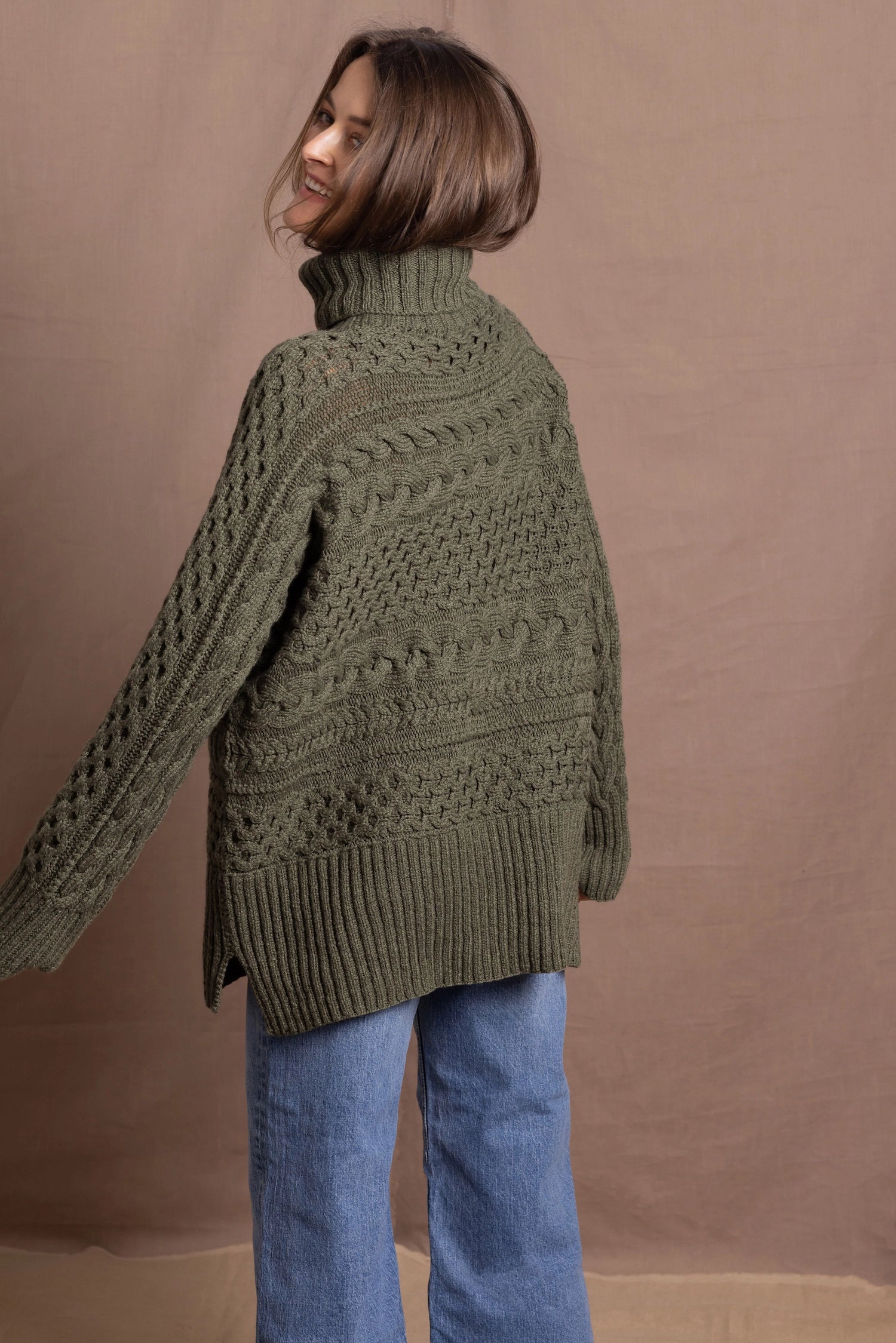 a lady wears a 100% cashmere aran sweater in fern green