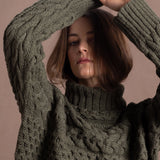 a lady wears a 100% cashmere aran sweater in fern green