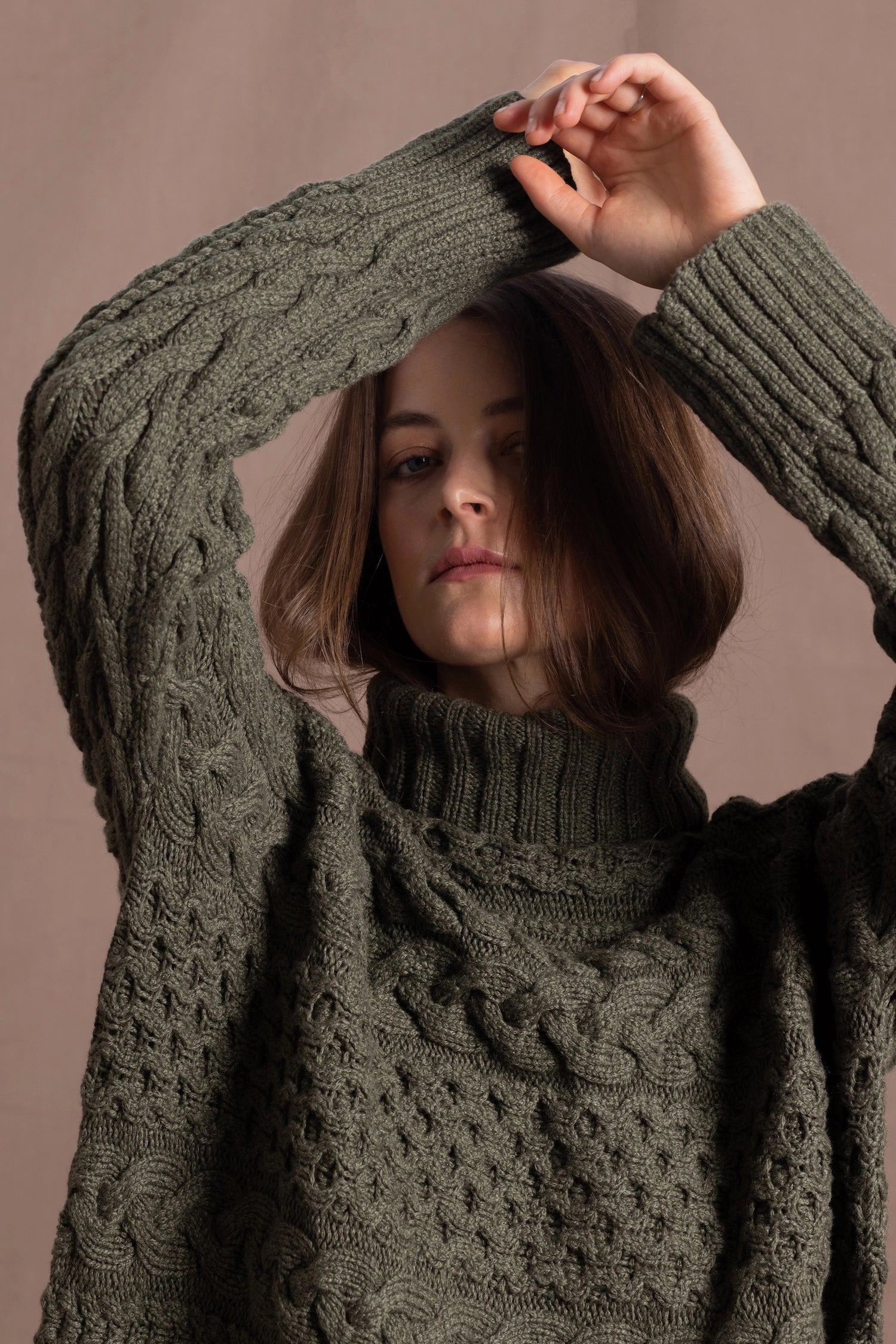 a lady wears a 100% cashmere aran sweater in fern green