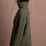 a lady wears a 100% cashmere aran sweater in fern green