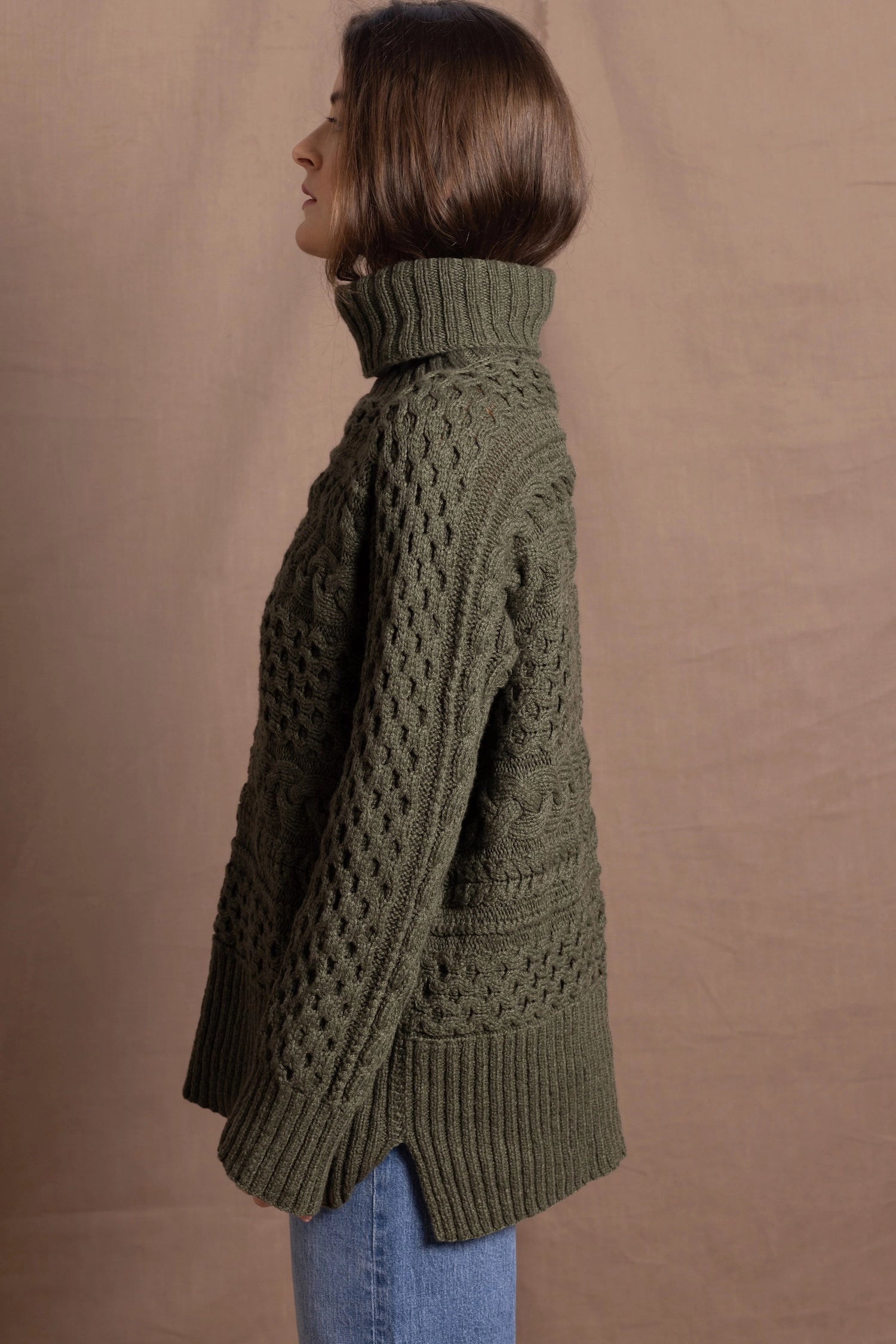 a lady wears a 100% cashmere aran sweater in fern green