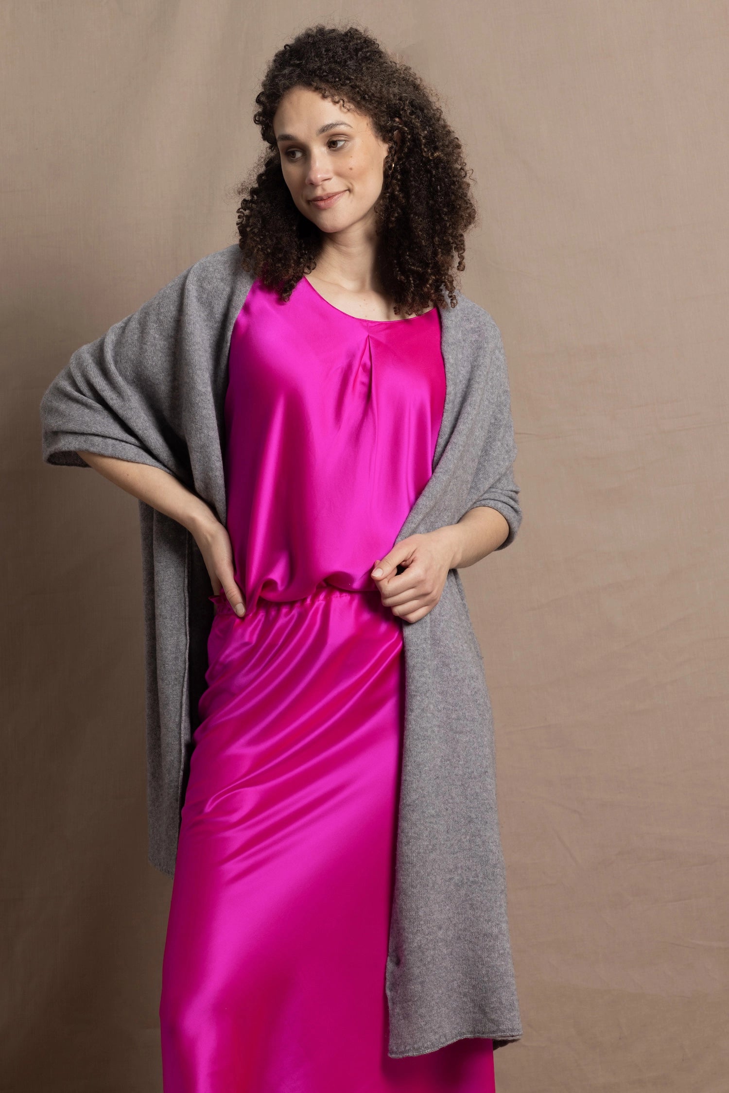Lady wears large cashmere wrap shawl in Grey against bright pink silk clothing