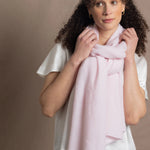 Lady wears luxurious cashmere wrap scarf in pale pink