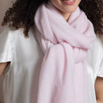 Lady wears luxurious cashmere wrap scarf in pale pink