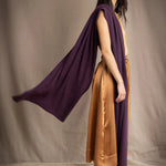 a woman wearing a large cashmere wrap shawl in dark purple over a bronze silk dress