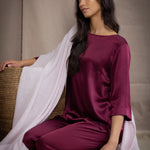 a woman wearing a large cashmere wrap shawl in pale pink over burgundy silk top and trousers