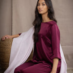 a woman wearing a large cashmere wrap shawl in pale pink over burgundy silk top and trousers
