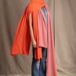 a woman wears a large cashmere wrap shawl in bright orange layered with a cashmere wrap in dusty rose pink