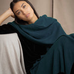a woman wearing a large cashmere wrap shawl in teal blue