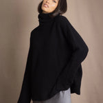 Woman wearing a black cashmere fisherman turtleneck sweater jumper with pewter silk skirt