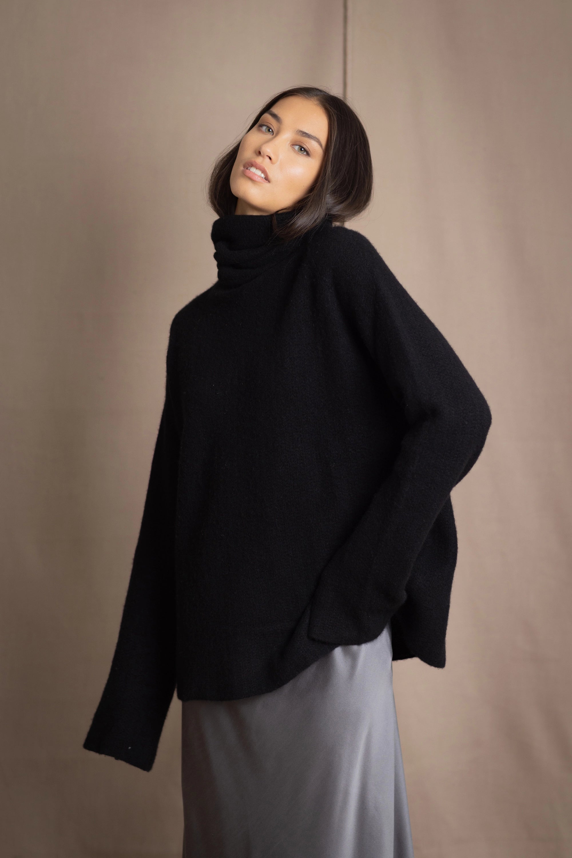 Woman wearing a black cashmere fisherman turtleneck sweater jumper with pewter silk skirt