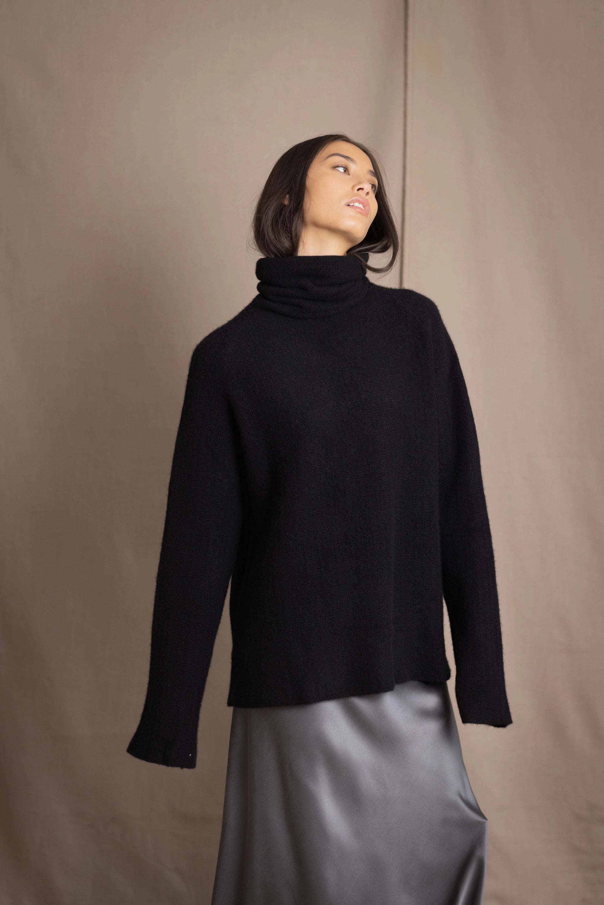 Woman wearing a black cashmere fisherman turtleneck sweater jumper with pewter silk skirt