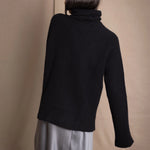 Woman wearing a black cashmere fisherman turtleneck sweater jumper with pewter silk skirt