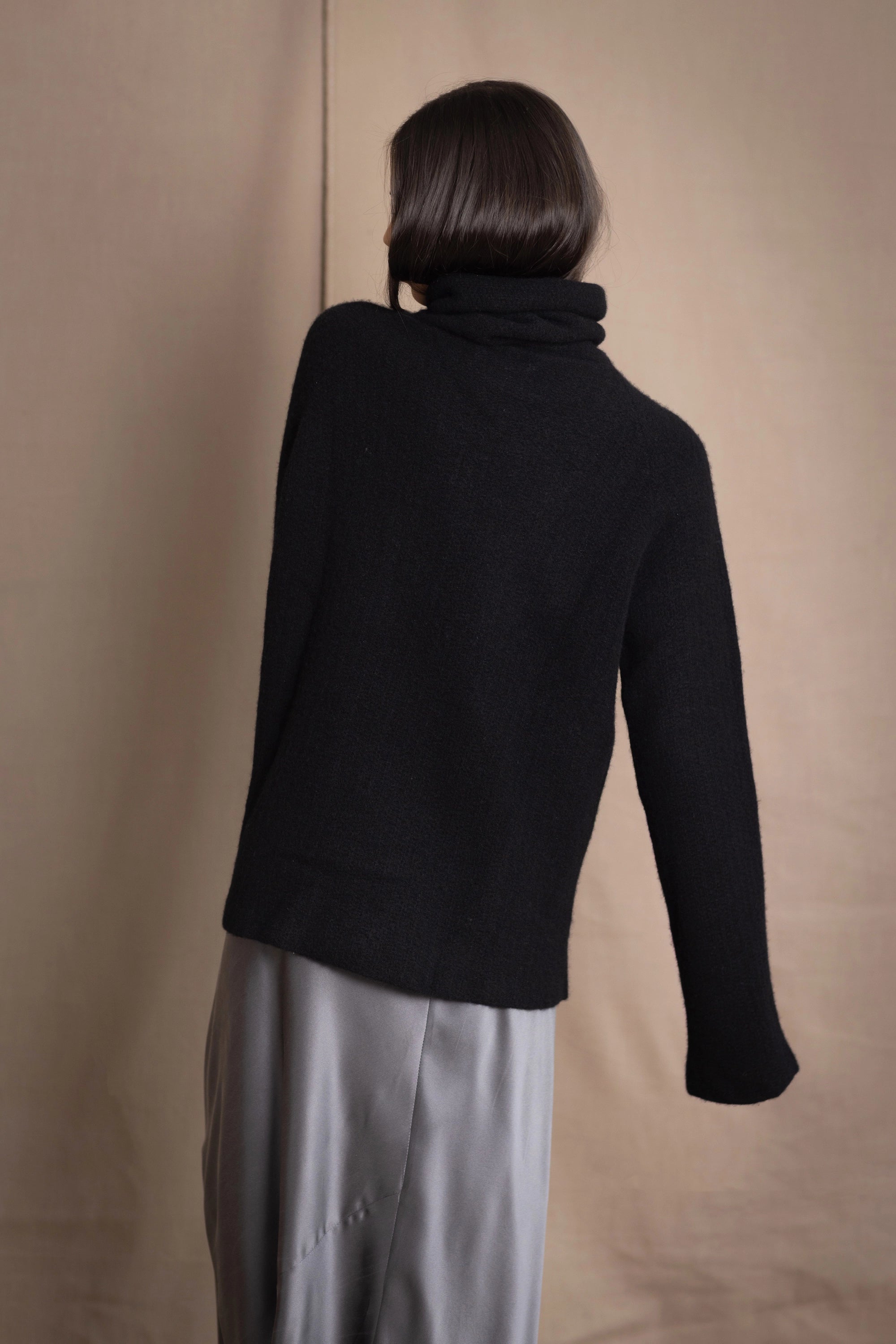 Woman wearing a black cashmere fisherman turtleneck sweater jumper with pewter silk skirt