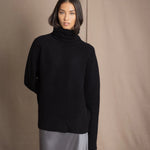 Woman wearing a black cashmere fisherman turtleneck sweater jumper with pewter silk skirt