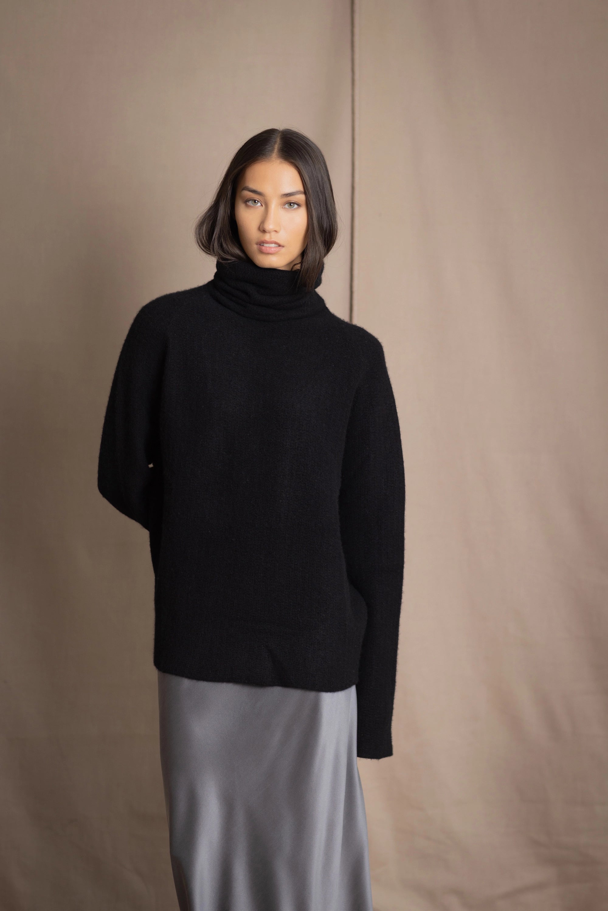 Woman wearing a black cashmere fisherman turtleneck sweater jumper with pewter silk skirt