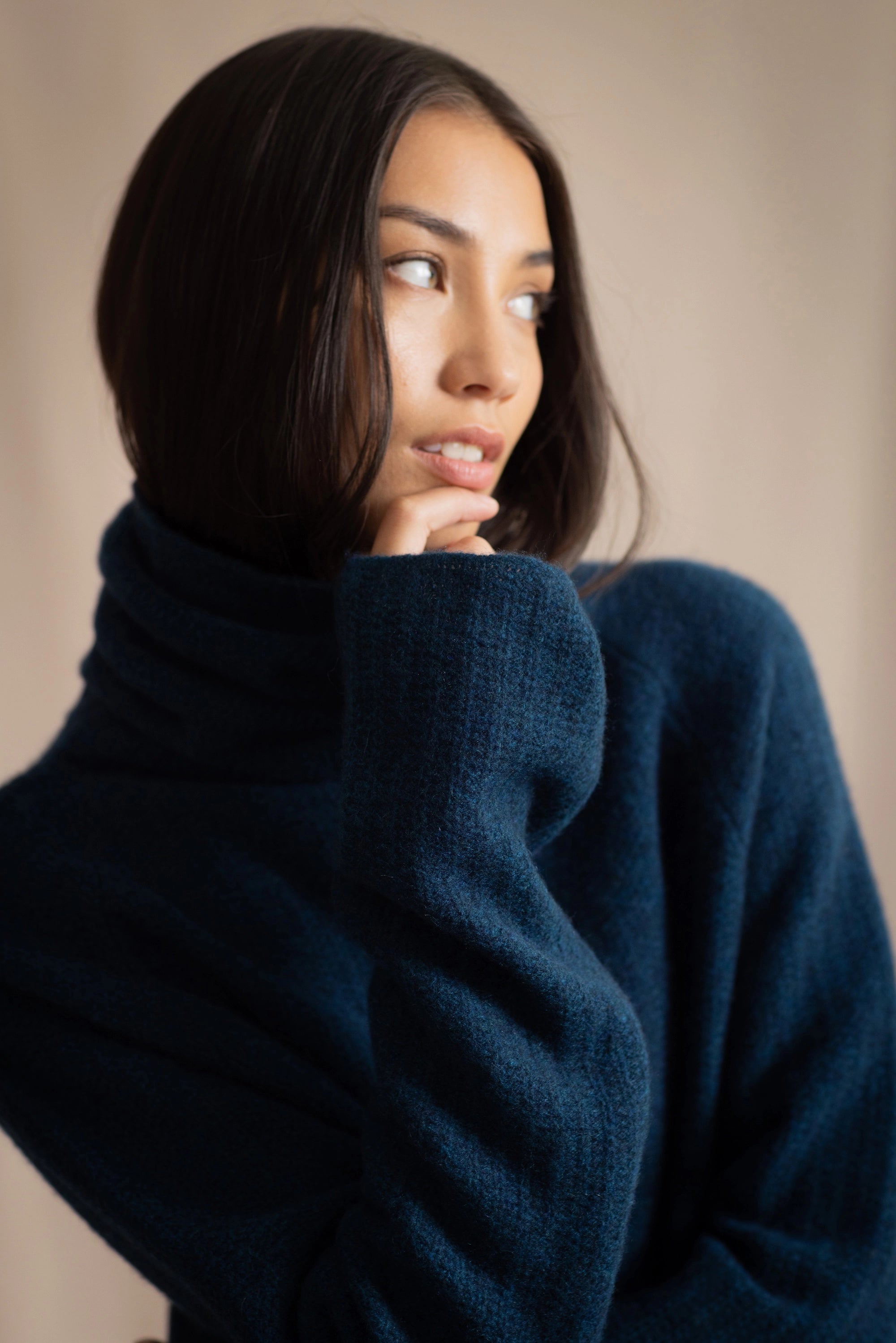Woman wearing a cashmere fisherman turtleneck sweater in teal blue