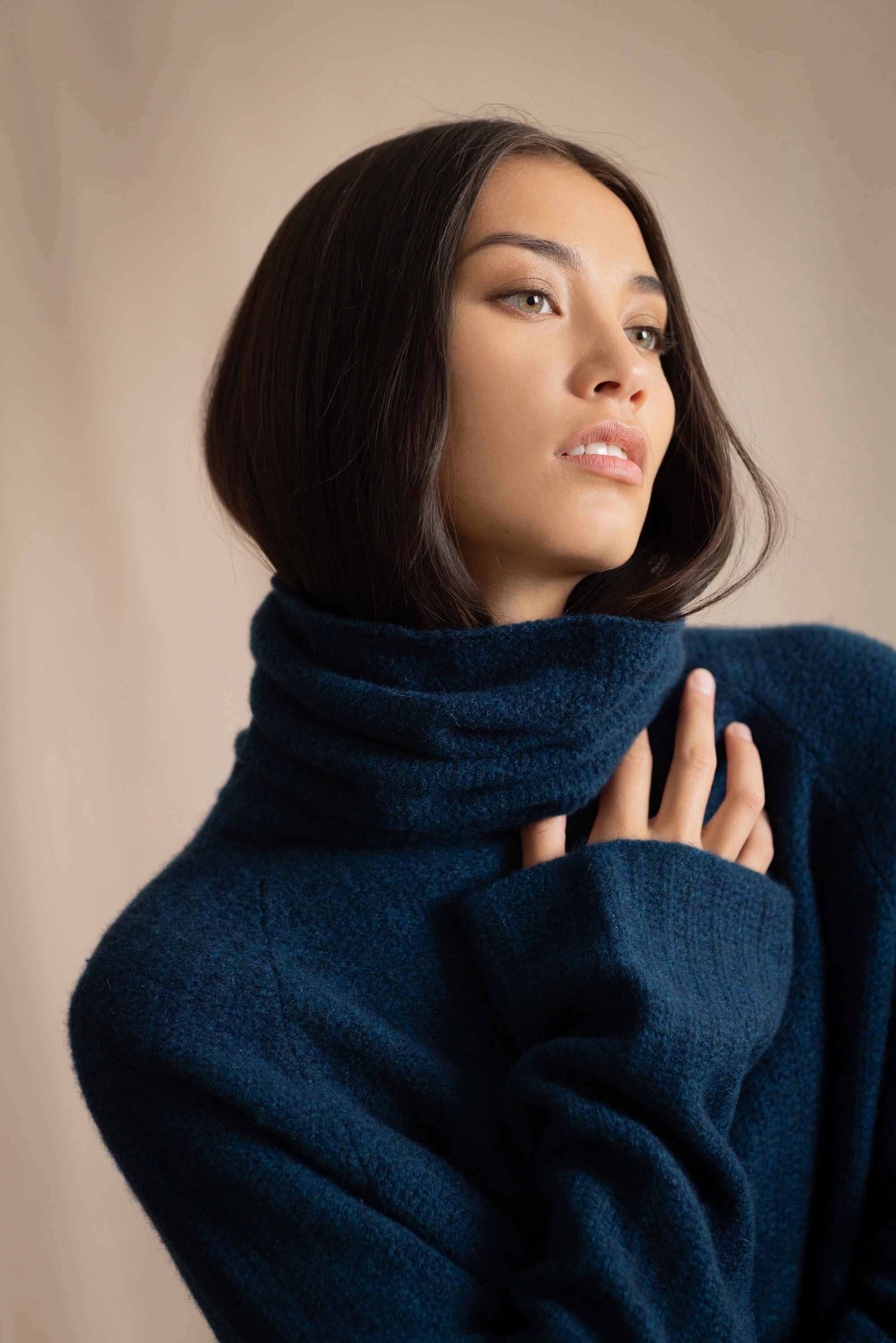 Woman wearing a cashmere fisherman turtleneck sweater in teal blue