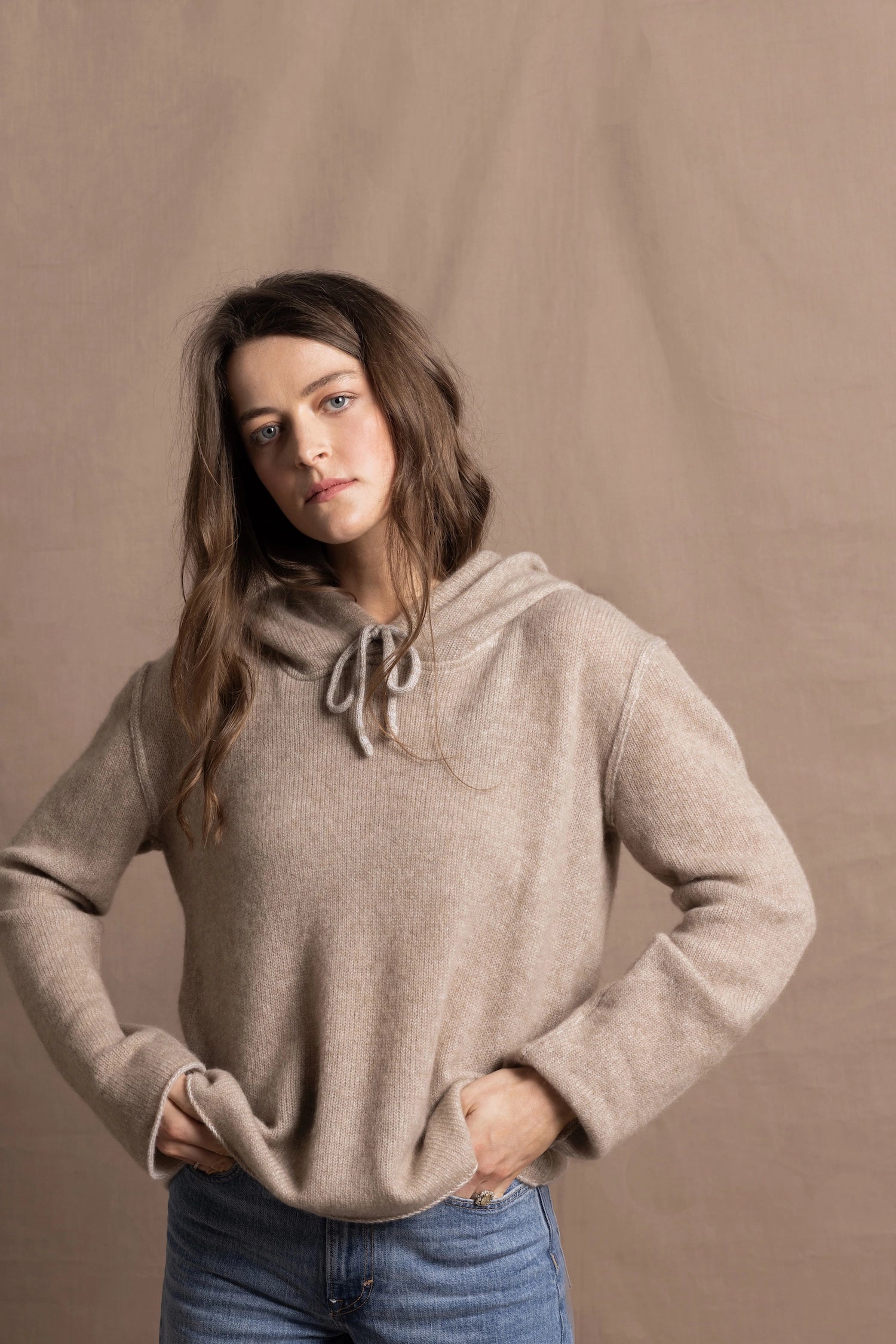 a woman wears a pure, 100% cashmere sweater in beige with jeans