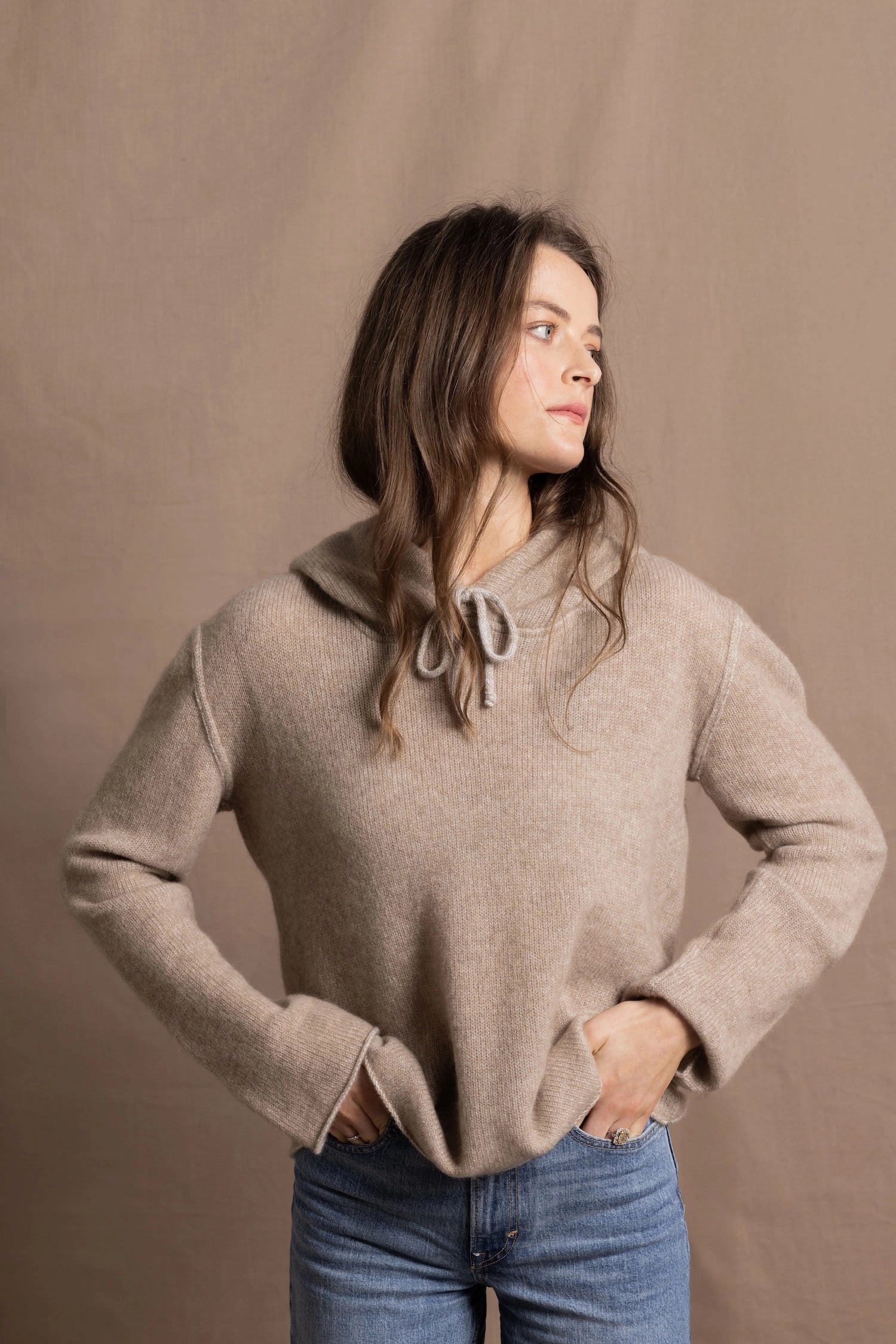 a woman wears a luxury cashmere hoodie in beige with jeans