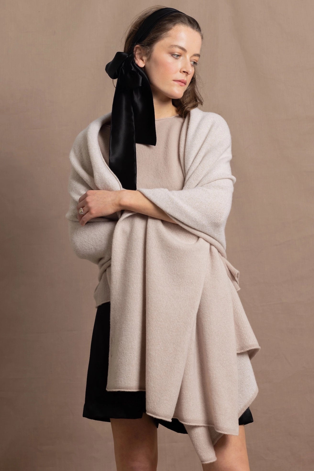 A woman wears a large cashmere shawl in beige over a matching cashmere tee