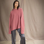 woman wearing an oversized cashmere sweater with hood in dusty pink rose colour and dark grey pewter silk trousers