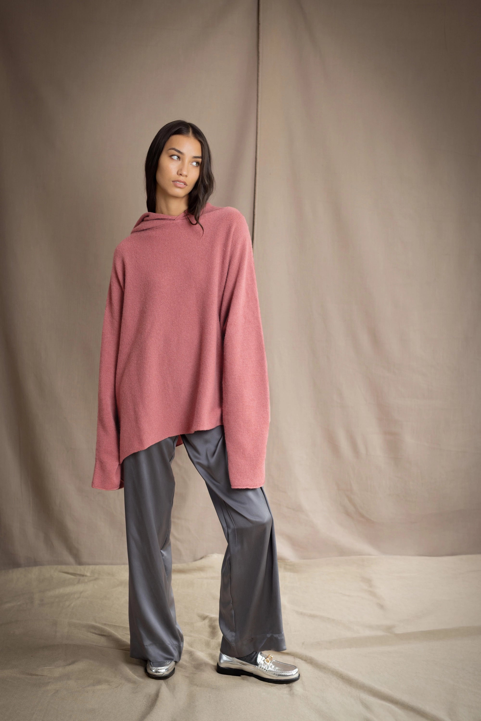 woman wearing an oversized cashmere sweater with hood in dusty pink rose colour and dark grey pewter silk trousers