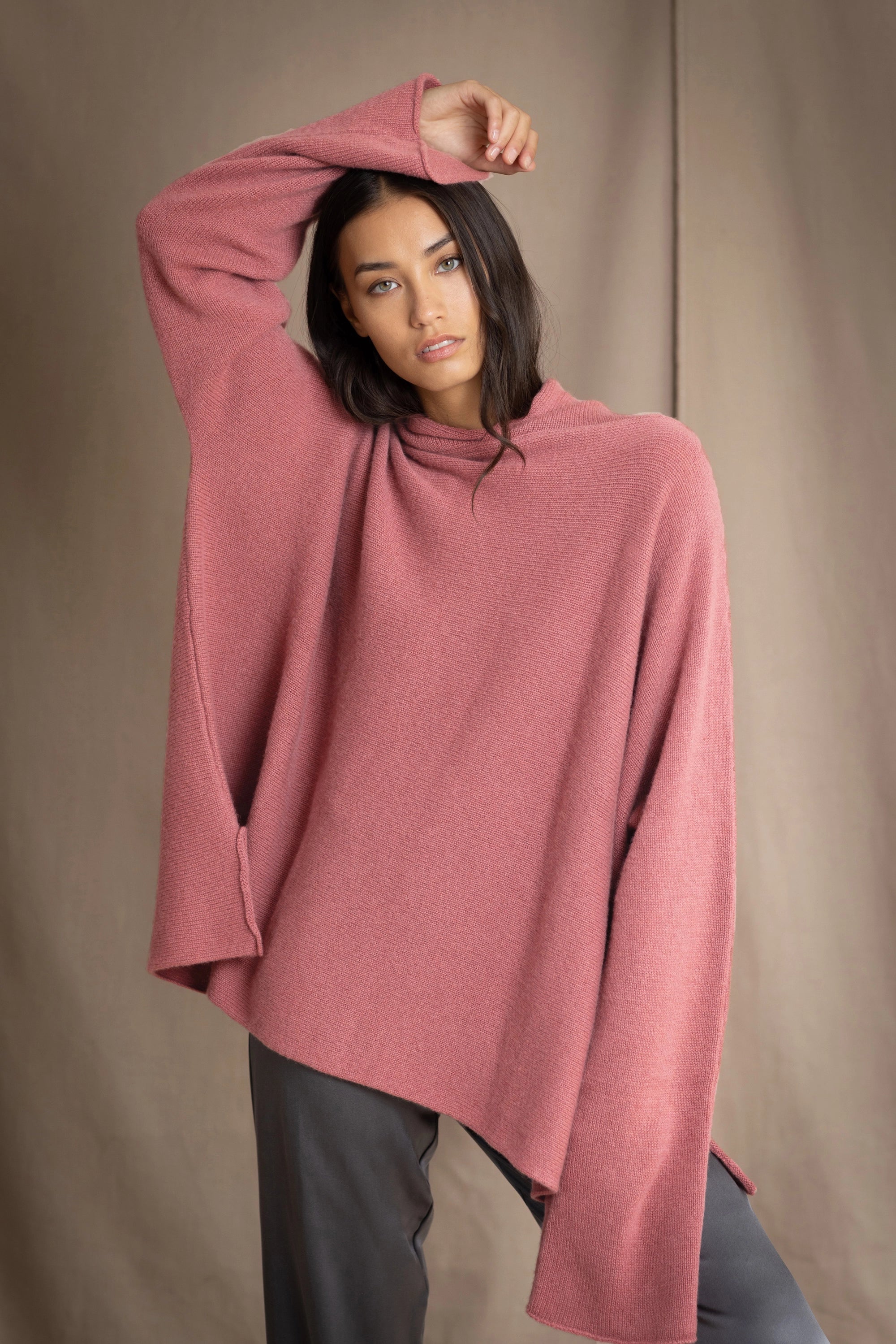 woman wearing an oversized cashmere sweater with hood in dusty pink rose colour with silk trousers in pewter