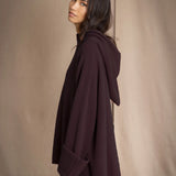 Woman wearing a dark purple oversized hooded sweater jumper