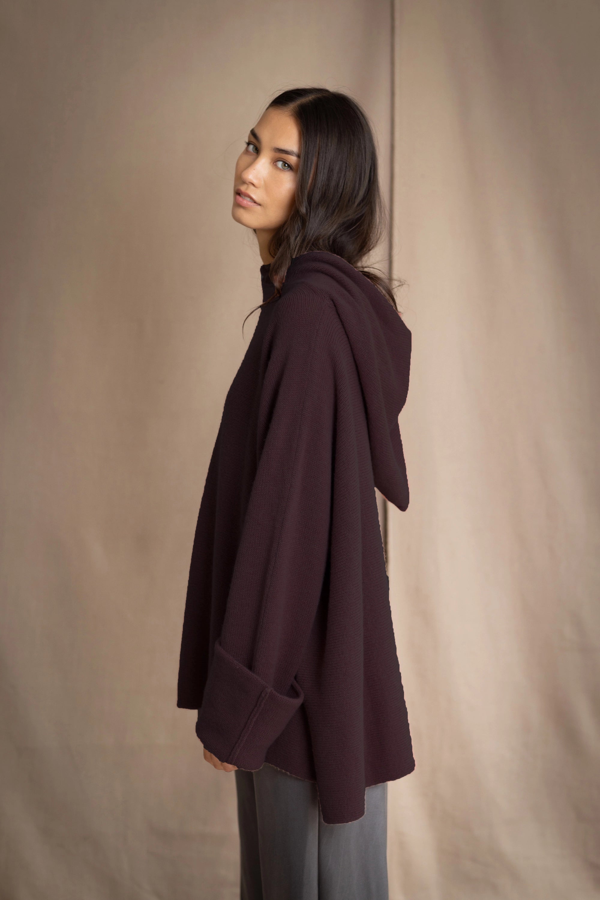 Woman wearing a dark purple oversized hooded sweater jumper