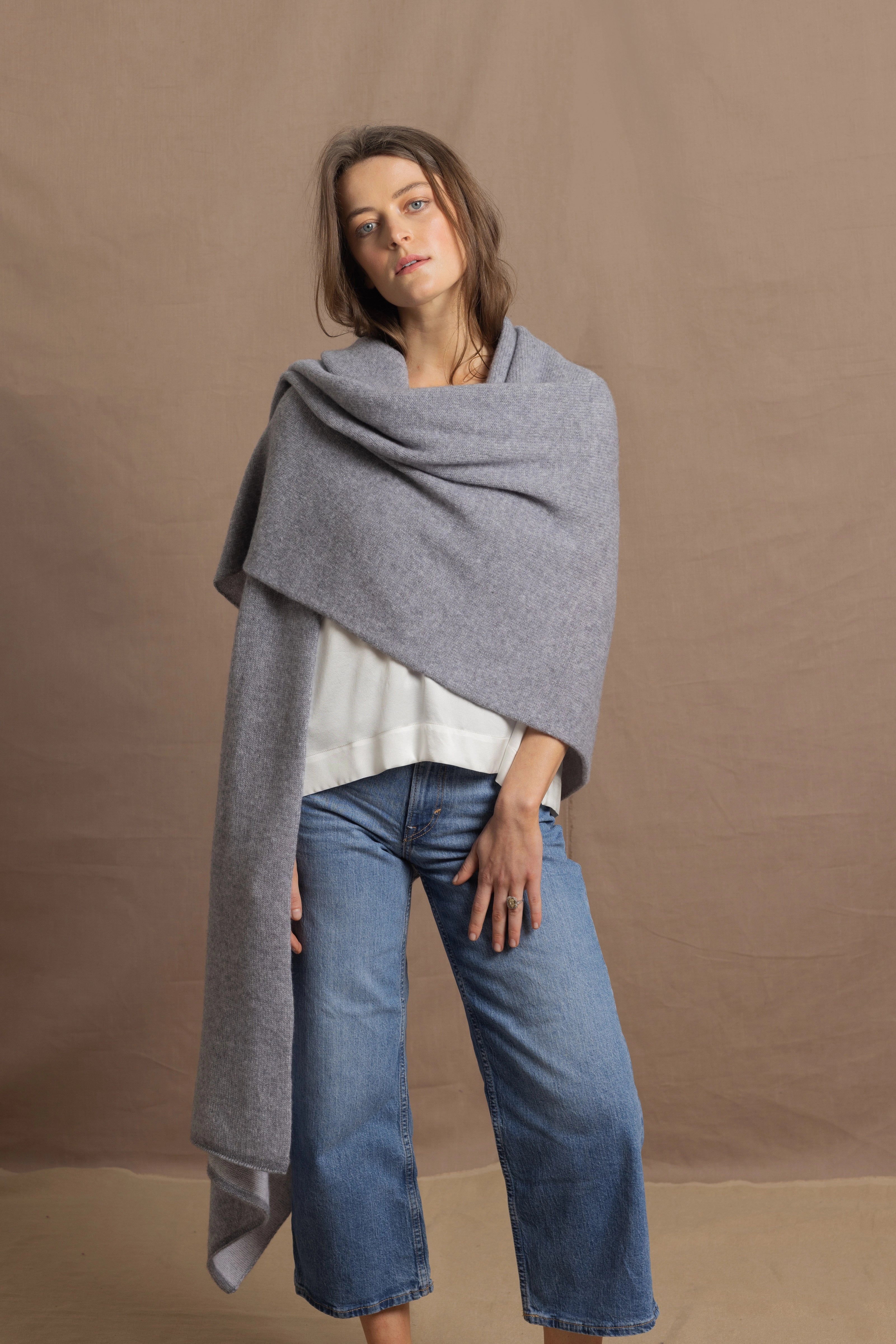 A woman wears a 100% cashmere wrap shawl in grey