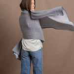 A woman wears a 100% cashmere wrap shawl in grey
