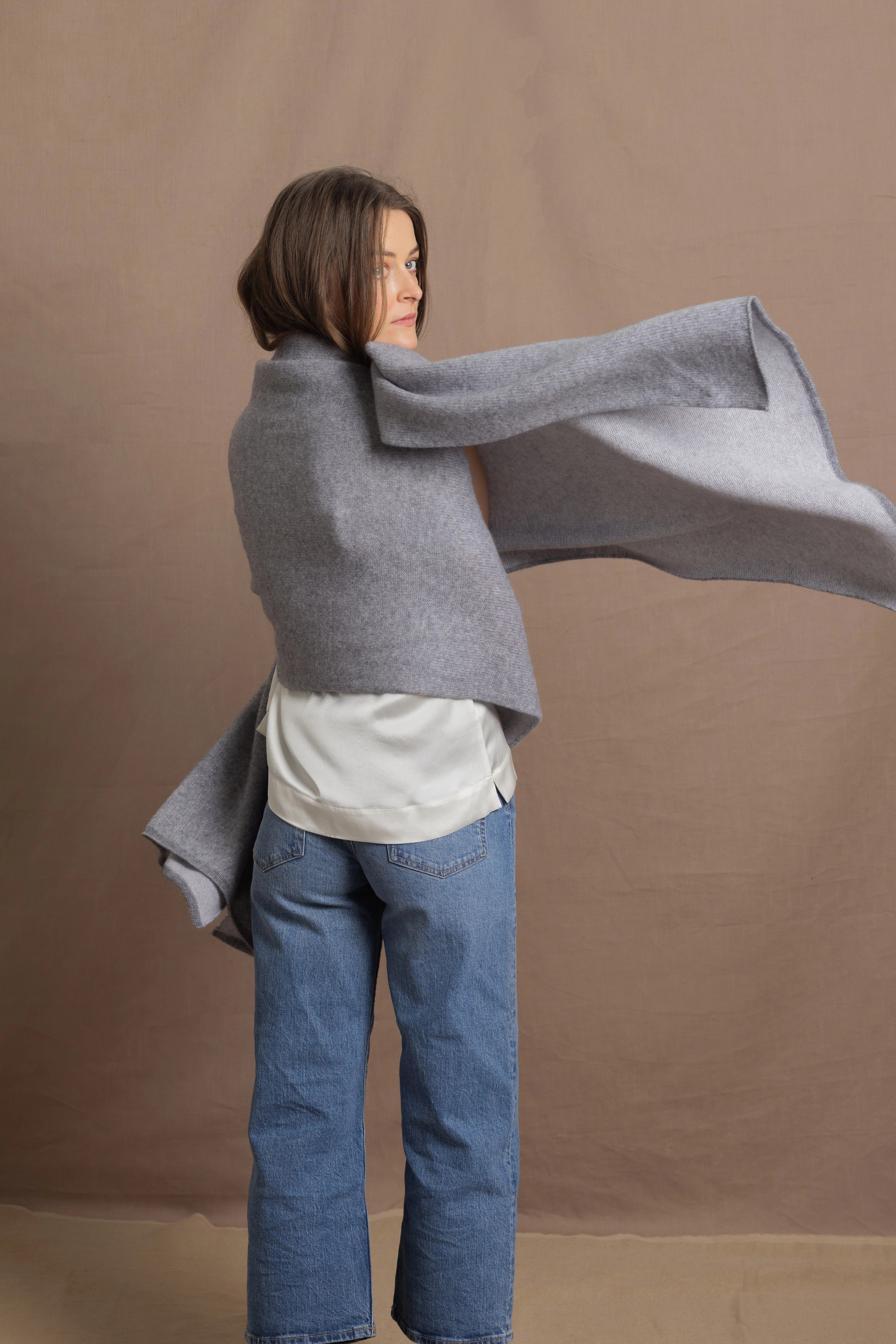 A woman wears a 100% cashmere wrap shawl in grey