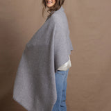 A woman wears a 100% cashmere wrap shawl in grey