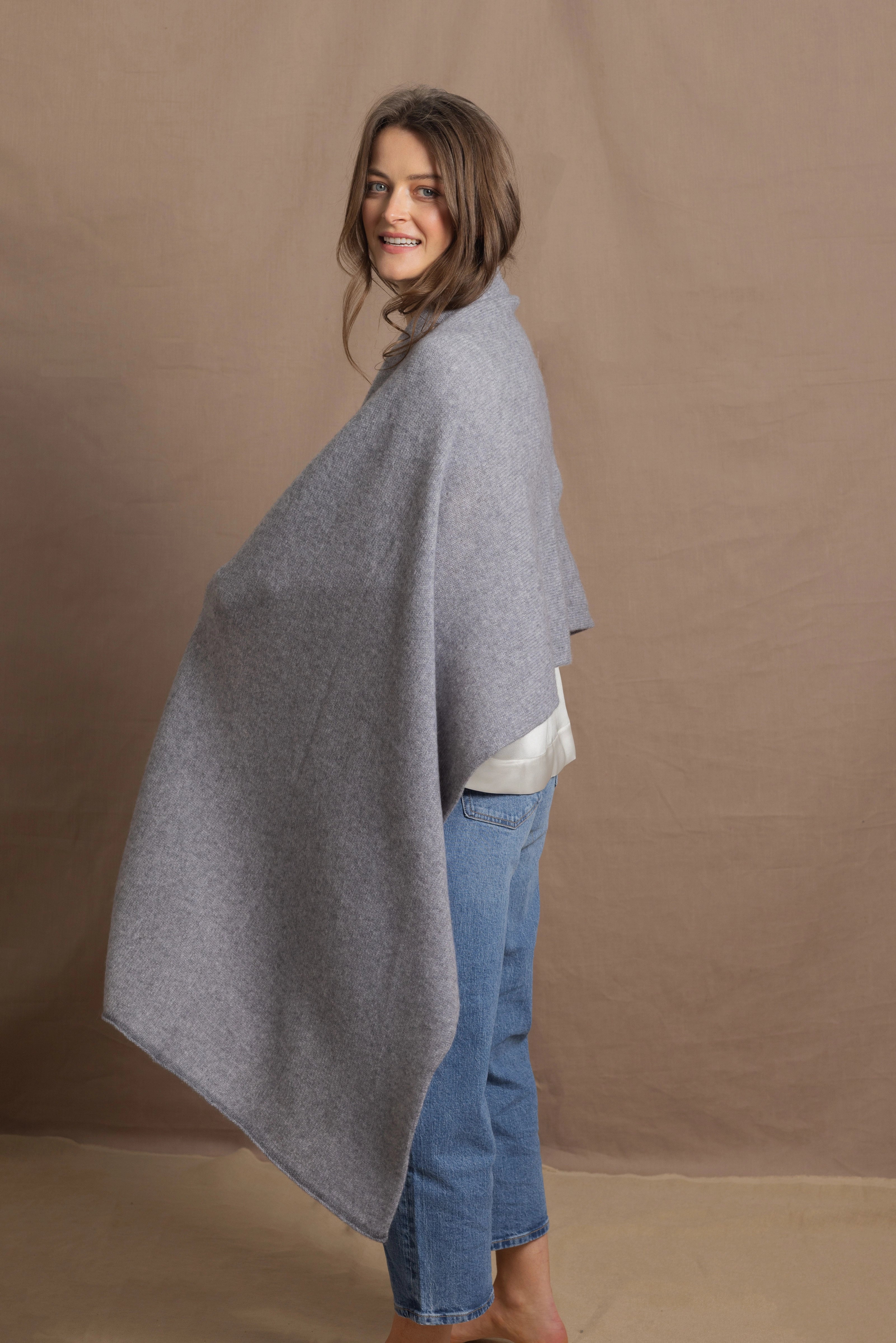 A woman wears a 100% cashmere wrap shawl in grey