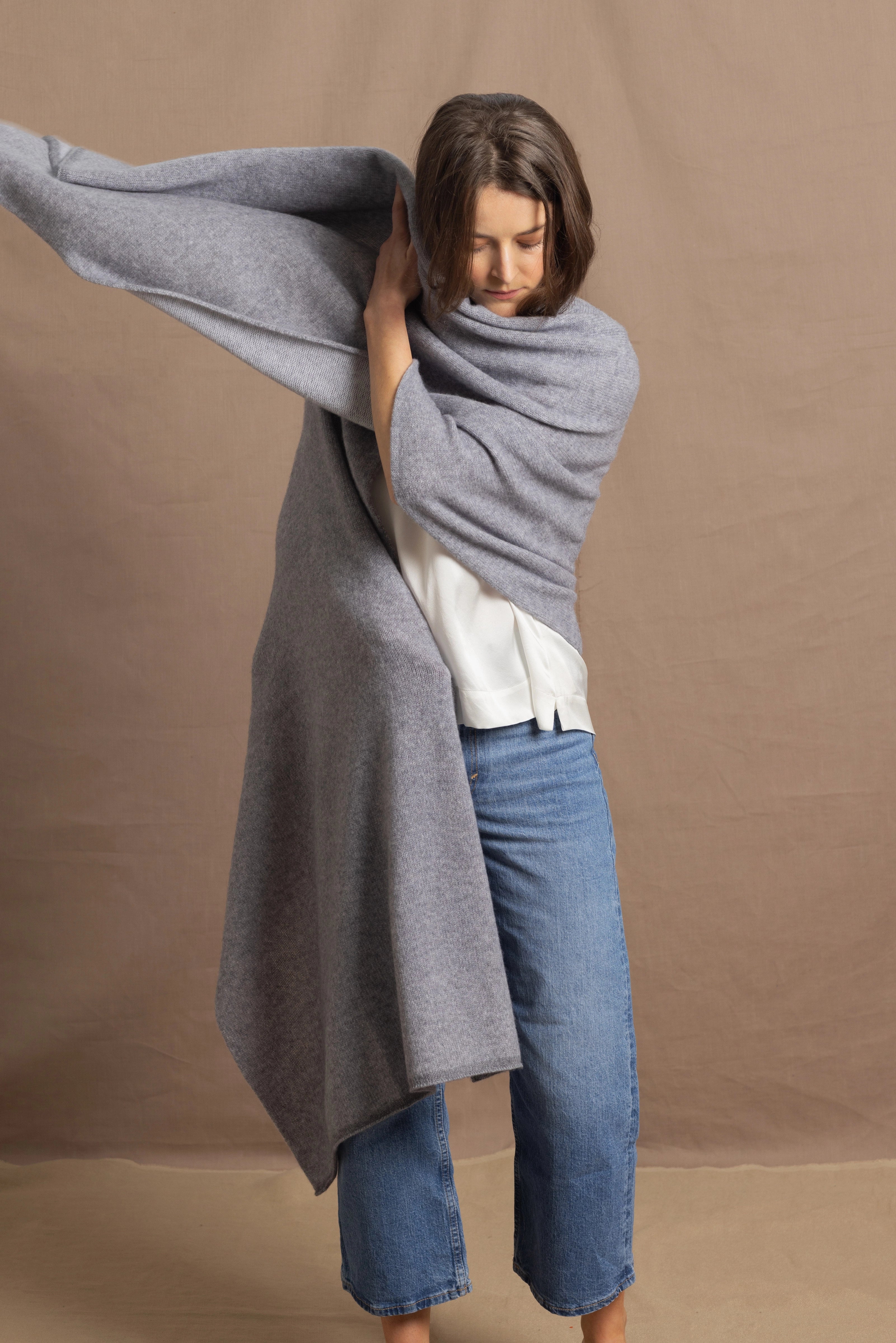 A woman wears a 100% cashmere wrap shawl in grey