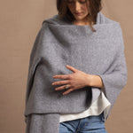 A woman wears a 100% cashmere wrap shawl in grey