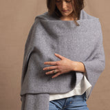 A woman wears a 100% cashmere wrap shawl in grey