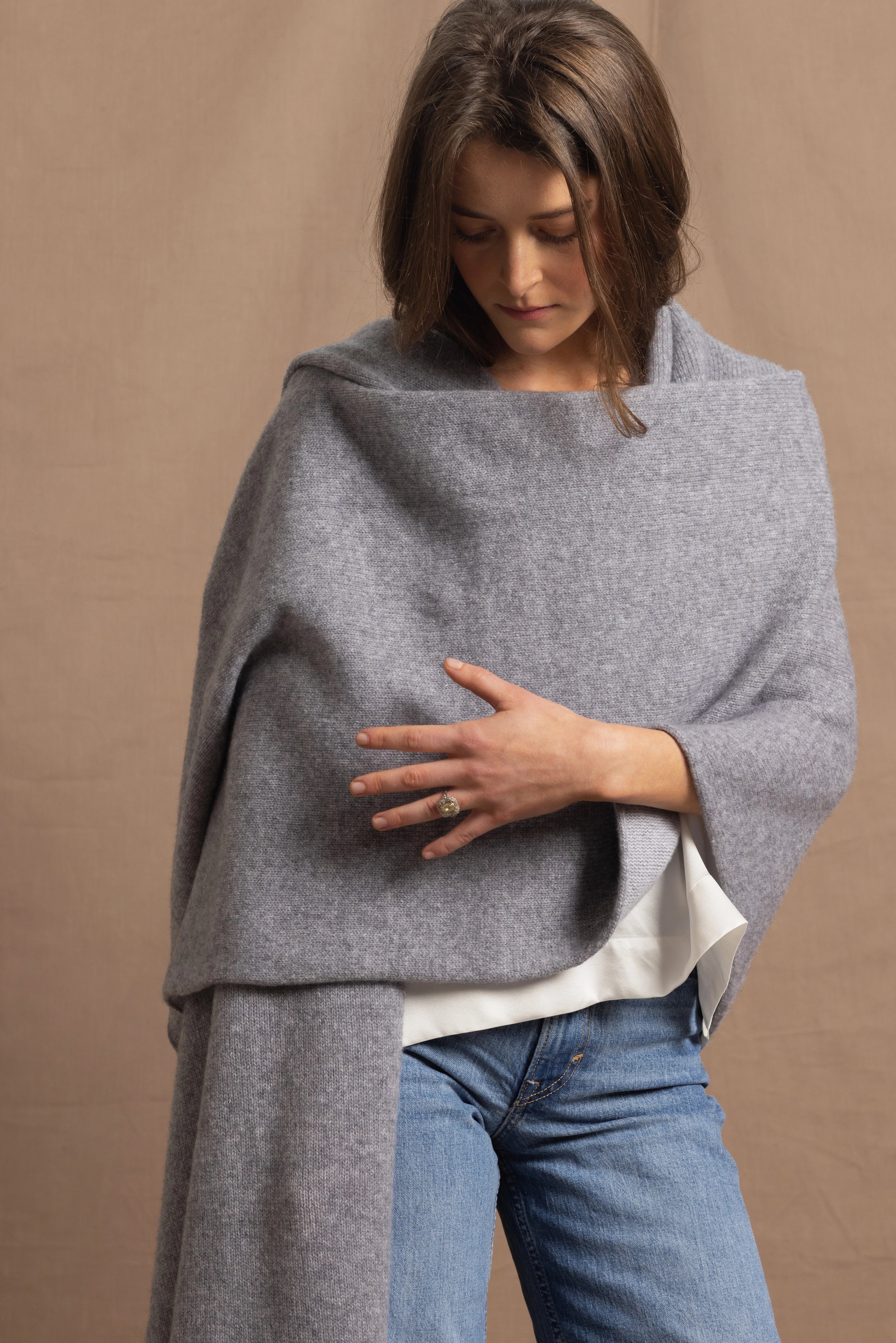 A woman wears a 100% cashmere wrap shawl in grey