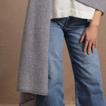 A woman wears a 100% cashmere wrap shawl in grey