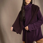 Woman wearing a cashmere fisherman turtleneck sweater in dark purple with bronze silk trousers and a brown and dark purple reversible cashmere scarf