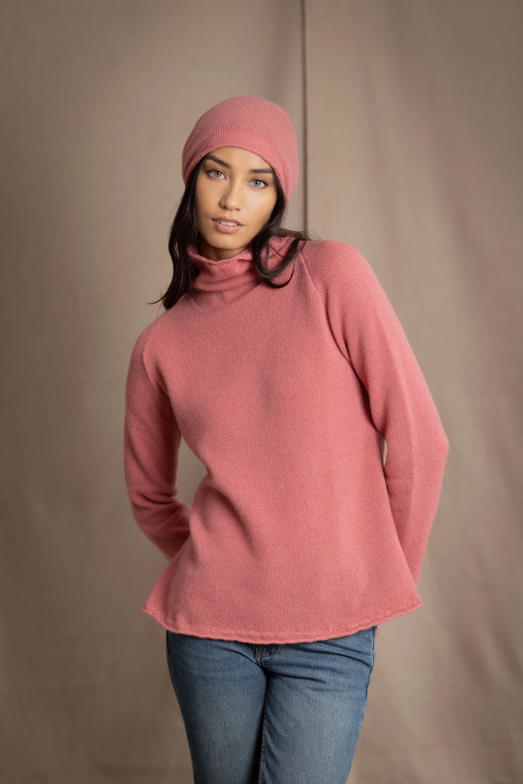 a woman wearing a cashmere turtleneck sweater in dusty rose pink and matching cashmere beanie hat in dusty rose pink