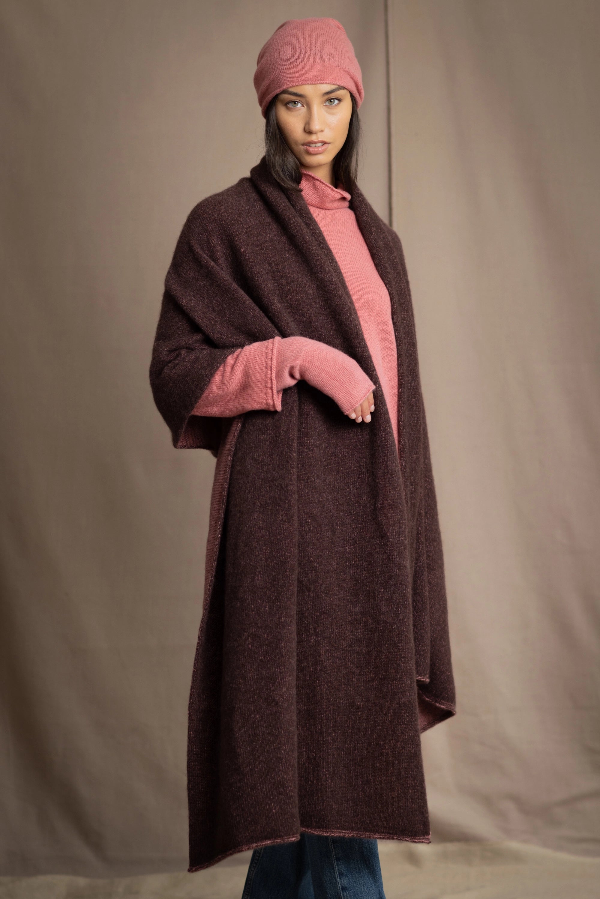 woman wears a long cashmere wrap shawl in dark brown and dusty rose pink with cashmere beanie hat in dusty rose pink